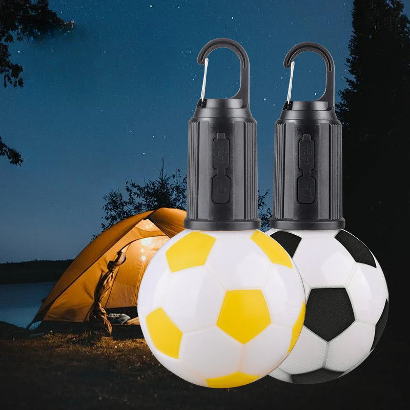 Luz LED Balón de Fútbol – Portátil y Recargable Type-C en uso durante campamento nocturno con tienda iluminada al fondo.